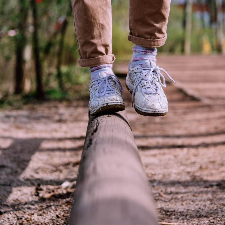 Balancing on a log beam in a forest.