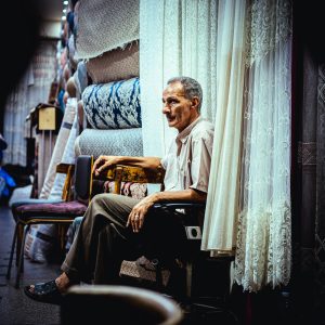 An older man sitting in a chair, representing the everyday movement studied in healthy aging research