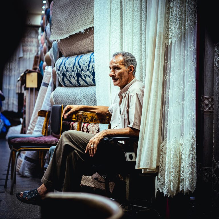 An older man sitting in a chair, representing the everyday movement studied in healthy aging research