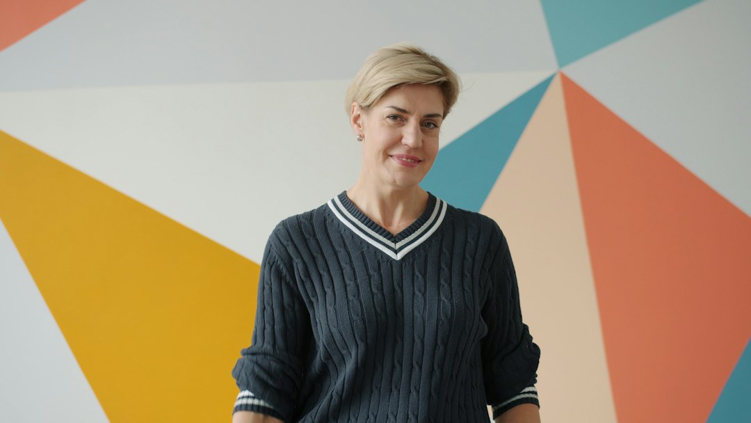 A confident woman smiling against a colorful wall