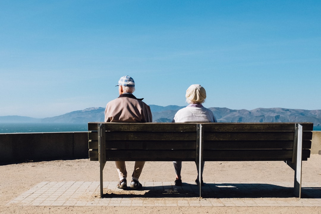 A couple sitting on a bench facing the sea, relaxing outdoors