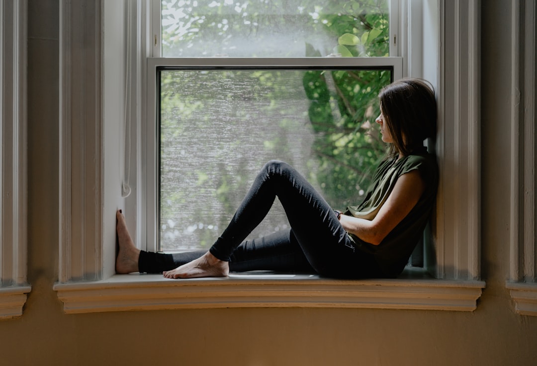 A woman sitting quietly by a window, lost in thought