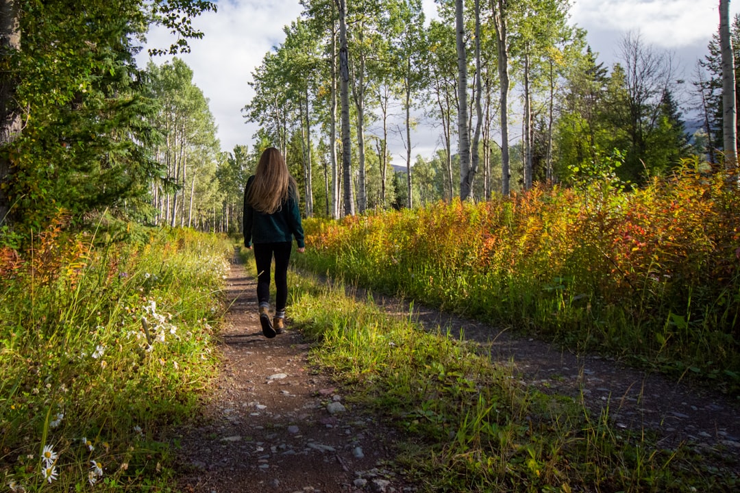A woman walking along a path between trees, without a phone