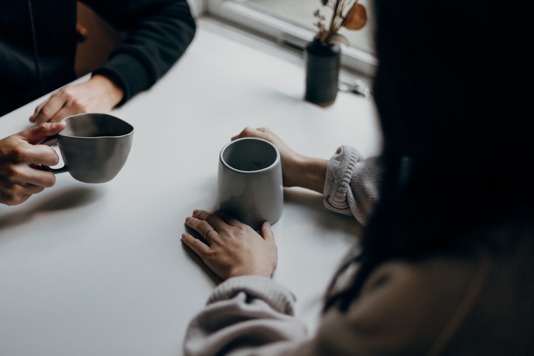 Two people holding mugs at a table