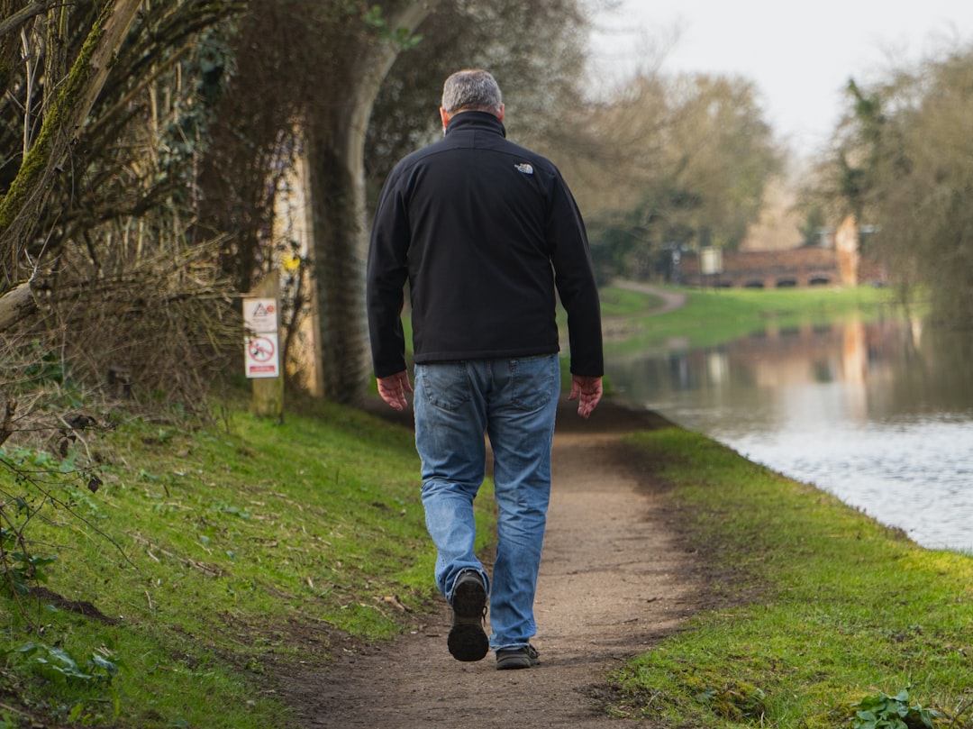 A man walking on a pathway near a river