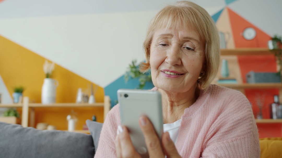 An older woman smiling while looking at her smartphone