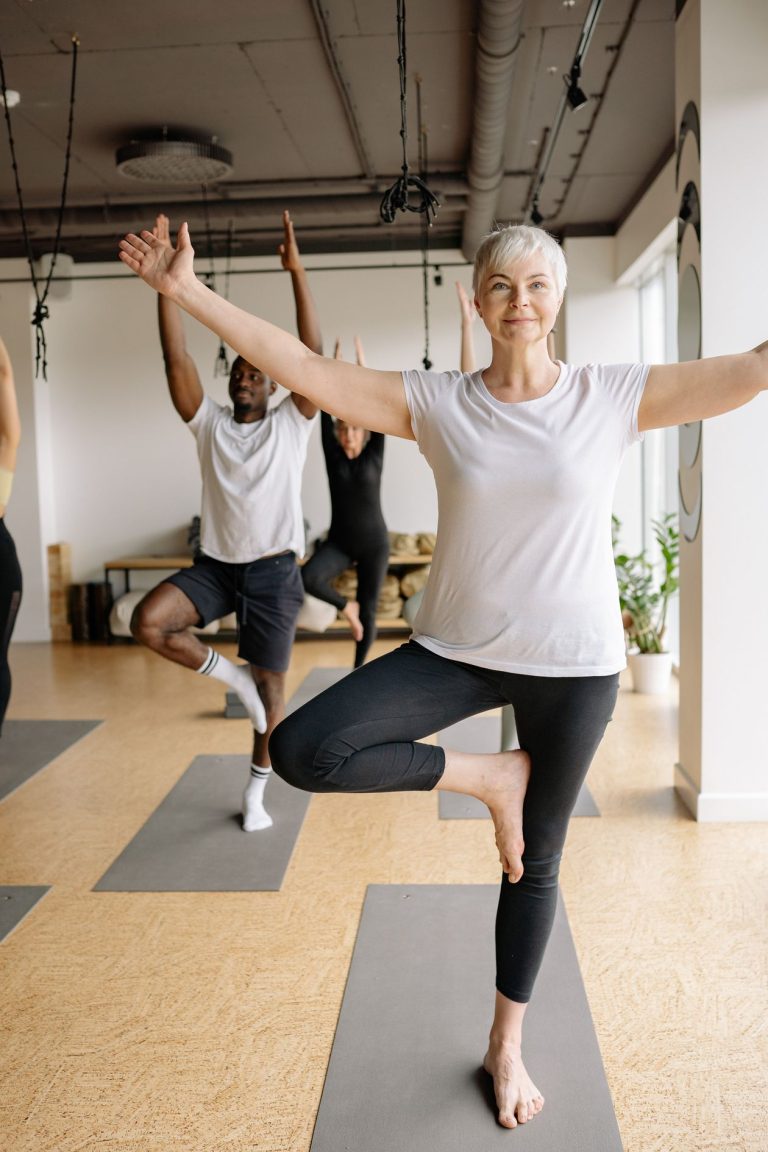 Elderly woman practising a balance yoga pose in a calm studio