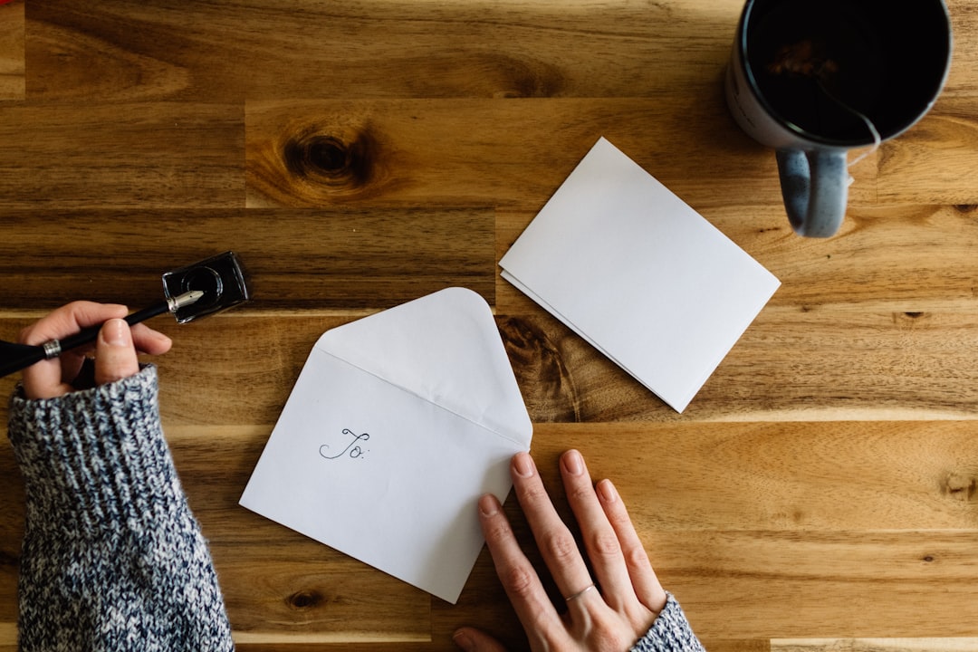 A person writing a handwritten note beside a cup of coffee