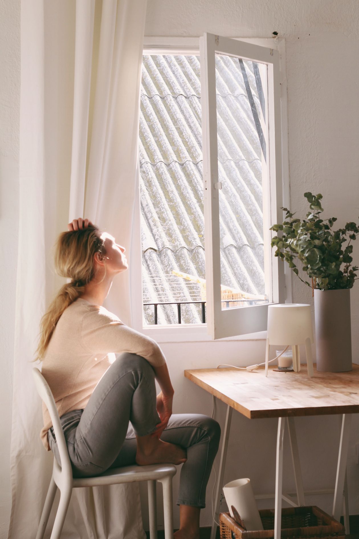 Woman sitting on a chair next to a window, reflective